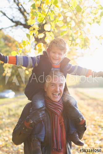 Portrait happy grandfather carrying grandson on shoulders in park