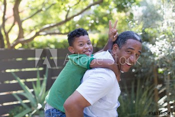 Portrait happy grandfather piggybacking grandson in backyard