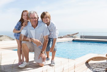 Portrait happy grandfather with grandkids at sunny swimming pool