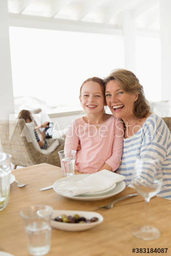 Portrait happy grandmother and granddaughter at table