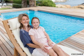 Portrait happy grandmother and granddaughter relaxing at poolside