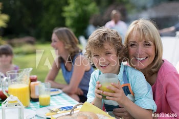 Portrait happy grandmother and grandson enjoying lunch at patio table