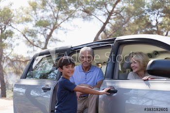 Portrait happy grandparents and grandson at car