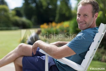 Portrait happy man relaxing in sunny lawn chair