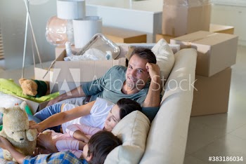 Portrait happy man with family on sofa in new house
