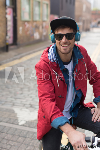 Portrait happy man with headphones and sunglasses riding bicycle