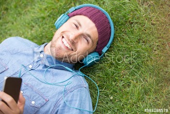 Portrait happy man with headphones listening to music in grass