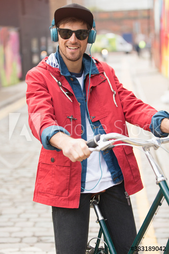 Portrait happy man with headphones riding bicycle on street
