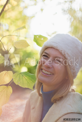 Portrait happy mature woman in fur hat in park