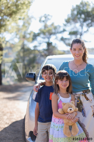 Portrait happy mother and children outside car at sunny roadside