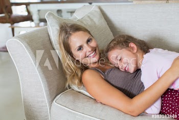 Portrait happy mother and daughter cuddling on sofa