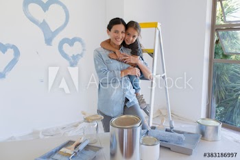 Portrait happy mother and daughter painting blue hearts on wall
