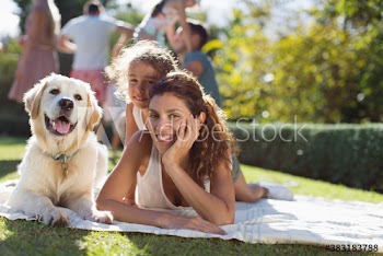 Portrait happy mother and daughter relaxing on sunny blanket with dog