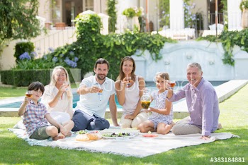 Portrait happy multi-generation family enjoying picnic in sunny garden