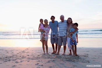 Portrait happy multi-generation family on sunset ocean beach