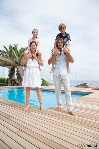 Portrait happy parents carrying kids on shoulders at poolside