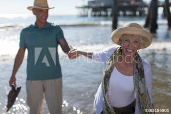 Portrait happy playful senior couple on sunny ocean beach