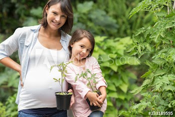 Portrait happy pregnant mother and daughter gardening