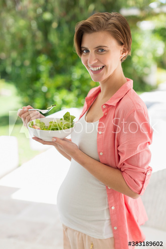 Portrait happy pregnant woman eating healthy salad