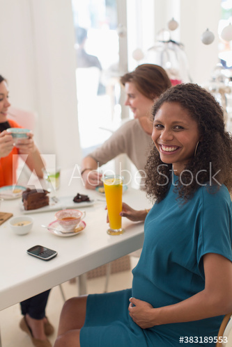 Portrait happy pregnant woman with friends in cafe