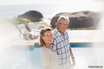 Portrait happy senior couple at sunny poolside