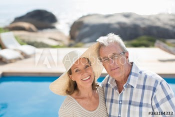 Portrait happy senior couple at sunny poolside