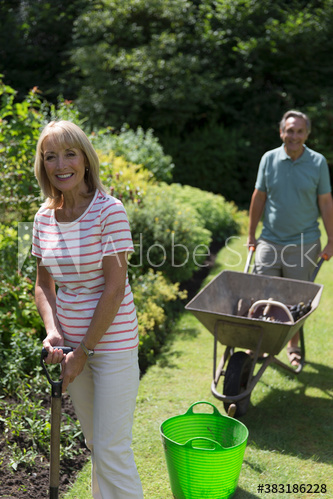 Portrait happy senior couple gardening in sunny backyard