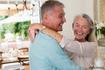 Portrait happy senior couple hugging in kitchen