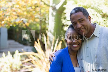 Portrait happy senior couple hugging in sunny yard