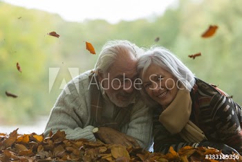 Portrait happy senior couple laying in autumn leaves
