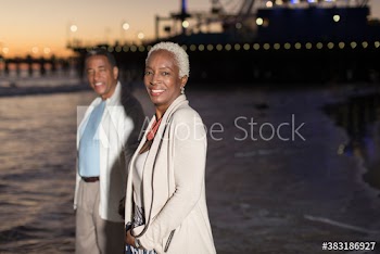 Portrait happy senior couple on ocean beach at dusk