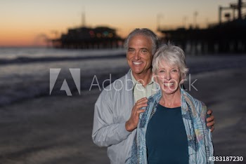 Portrait happy senior couple on ocean beach at dusk