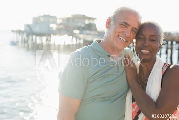 Portrait happy senior couple on sunny ocean pier