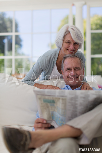 Portrait happy senior couple reading newspaper on sofa