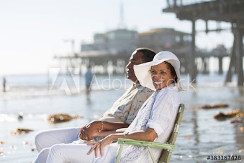 Portrait happy senior couple relaxing in lawn chairs on sunny beach
