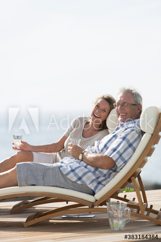 Portrait happy senior couple relaxing on lounge chairs