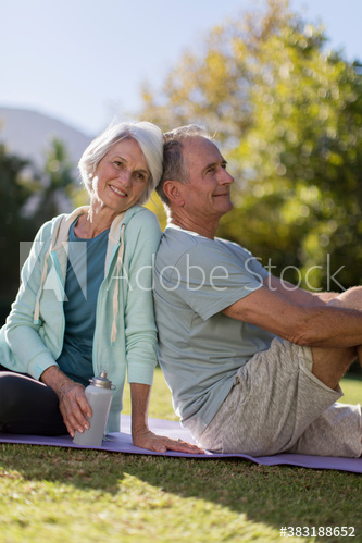 Portrait happy senior couple resting on yoga mat in grass