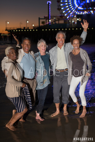 Portrait happy senior friends dancing on beach at night