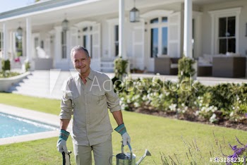 Portrait happy senior man gardening in sunny backyard