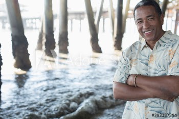 Portrait happy senior man on ocean beach below pier