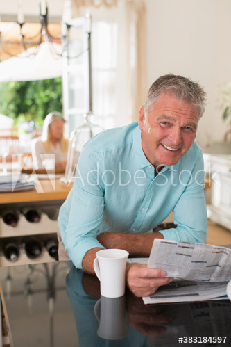 Portrait happy senior man reading newspaper and drinking coffee