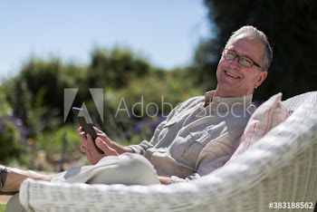 Portrait happy senior man using digital tablet in sunny garden