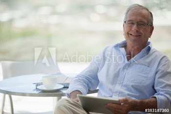 Portrait happy senior man using digital tablet on patio