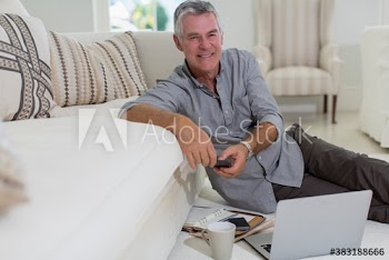 Portrait happy senior man using laptop on living room floor