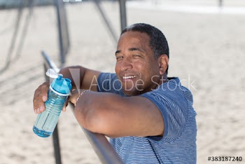 Portrait happy senior man with water bottle exercising on beach