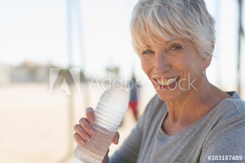 Portrait happy senior woman drinking cold bottled water