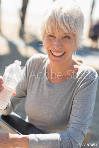 Portrait happy senior woman drinking water outdoors