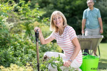 Portrait happy senior woman gardening in sunny backyard