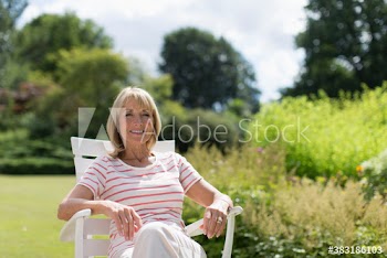 Portrait happy senior woman relaxing in sunny garden