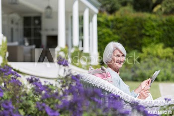 Portrait happy senior woman using digital tablet in sunny garden